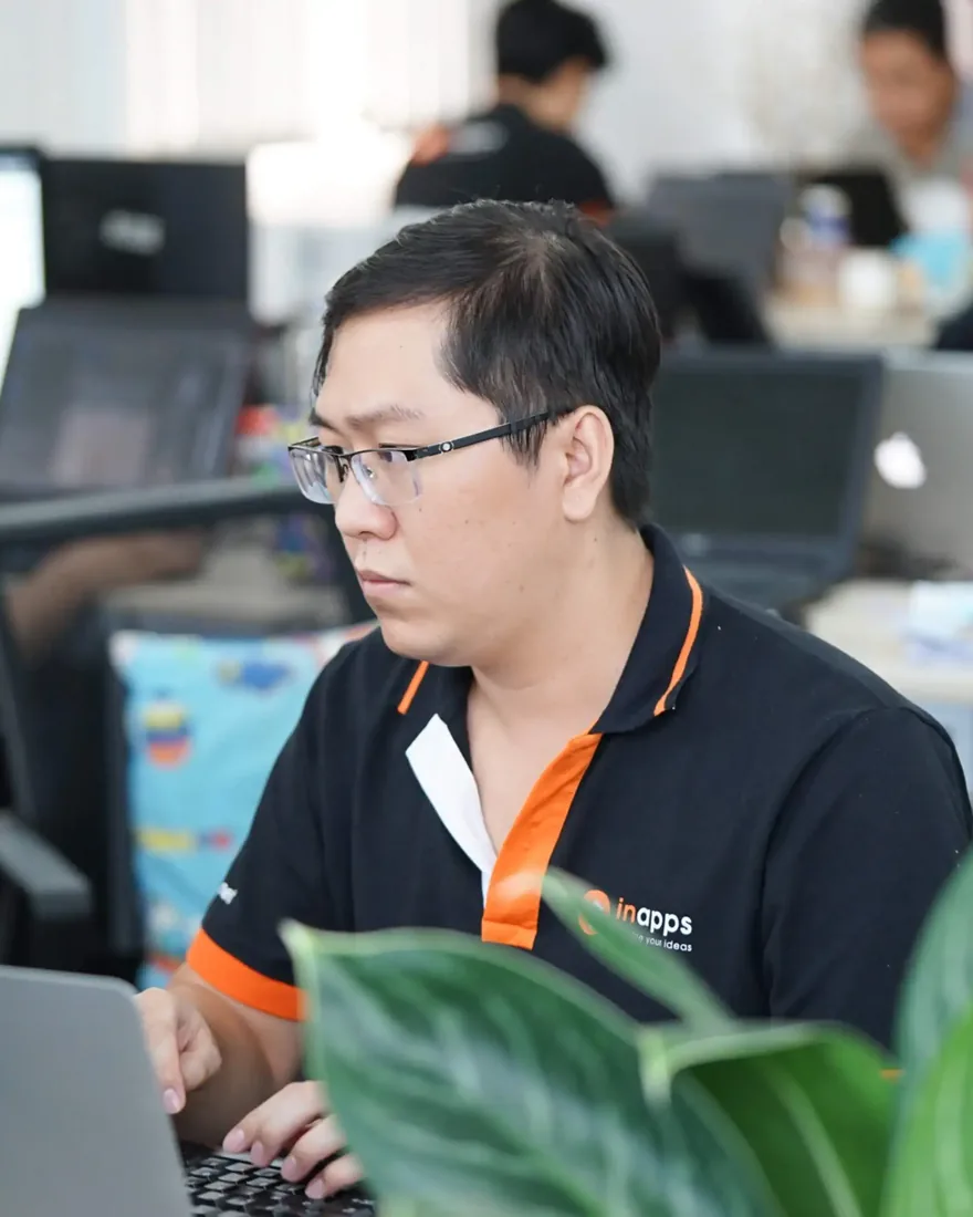An InApps engineer in the company polo at his laptop in the Ho Chi Minh City office